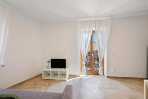a white living room with a tv on a table at Al Casel - Appartamento Collina in Torri del Benaco