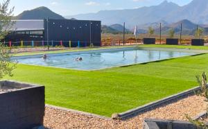 people swimming in a swimming pool with green grass at Karoo 62 Escape - A-frame in Ladismith