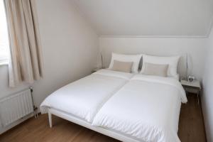 a white bed with white sheets and pillows at vakantiehuis met infraroodsauna no 10 in Breskens +15 photos