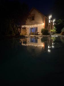 a house with lights around a swimming pool at night at Le Clos St Justin Votre étape sur la route des vacances à 10 mn de Center Parc et Chambord in Ligny-le-Ribault