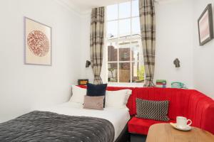 a bedroom with a red couch and a red chair at The Berkeley Square Hotel Bristol in Bristol