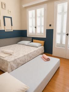 two beds in a room with two windows at Retro Apartment Patras in Patra