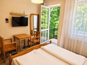 a bedroom with a bed and a table and a window at Platán Panzió in Dobogoko