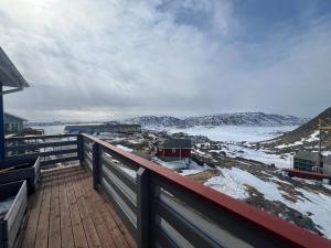 a wooden deck with a view of the snow covered ground at Arctic hostel in Qaqortoq