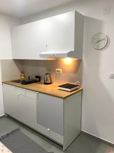 a kitchen with white cabinets and a clock on the wall at Apartman Beli Bagrem in Veliko Gradište