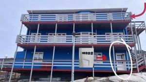 a large blue and red building on a beach at Arctic hostel in Qaqortoq