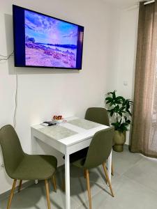 a white table with chairs and a tv on a wall at Apartman Beli Bagrem in Veliko Gradište +13 photos