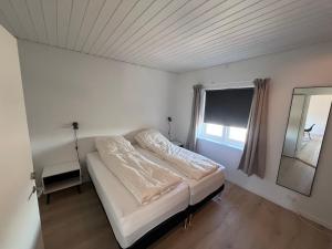 a white bedroom with a bed and a window at Arctic hostel in Qaqortoq