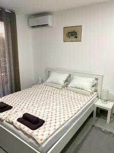 a white bedroom with a bed with a black blanket at Apartman Beli Bagrem in Veliko Gradište