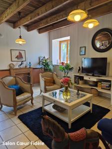a living room with a table and a tv at Manoir des Nobles Cœurs et Spa in Saint-Donan