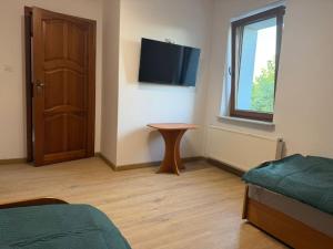 a room with a bed and a table and a television at Hostel in Piotrków Trybunalski