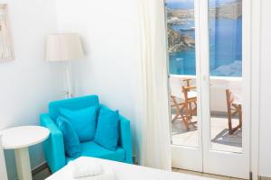 a room with a blue chair and a view of the ocean at Paradise Place Sifnos in Chrisopigi