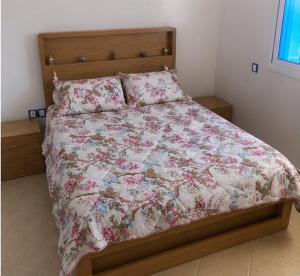 a bedroom with a bed with a floral bedspread and pillows at cosy and comfortable stay in Oued Laou
