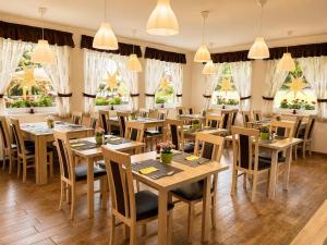 a restaurant with wooden tables and chairs and windows at Platán Panzió in Dobogoko