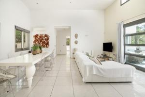 a white living room with white couches and a tv at Can Drago in Ibiza Town