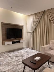 a living room with a television and a couch and a table at بريفير للشقق المخدومة - Privere Serviced Apartments in Riyadh