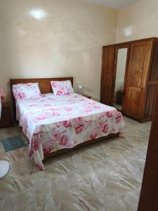 a bedroom with a bed with a pink bedspread at Le Rivage de Sérénité in Sali Nianiaral +10 photos