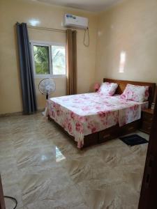 a bedroom with a bed and a fan and a window at Le Rivage de Sérénité in Sali Nianiaral