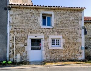 a stone building with a white door and two windows at Chambre d'hôte ColChris in Saint-Pierre-le-Vieux