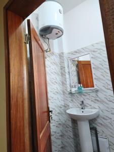 a bathroom with a sink and a toilet and a light at Le Rivage de Sérénité in Sali Nianiaral