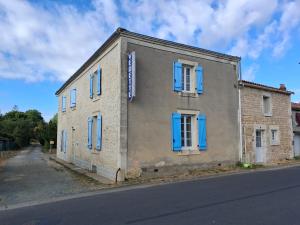 an old brick building with blue shutters on a street at Chambre d'hôte ColChris in Saint-Pierre-le-Vieux