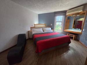 a bedroom with a bed with a red blanket and a window at Hotel Alcampo in Querétaro +65 photos