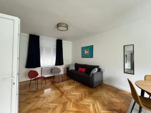 a living room with a black couch and a wooden floor at Pelso d'Oro apartmanház in Balatonföldvár