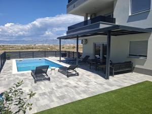 a patio with a pool and chairs and a house at Mima apartments in Povljana