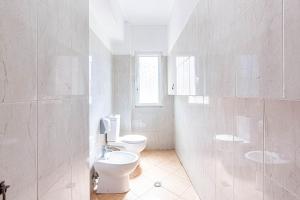 a white bathroom with two toilets and a window at Dhermi's Icon Big 1BR Apt 10 in Dhërmi