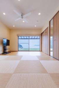 an empty living room with a ceiling fan and a large window at ヴィラ倉橋 in Kure