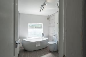 a white bathroom with a tub and a toilet at Spacious 3BR Family Home with Big Garden in Manchester