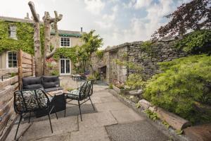 a patio with a table and chairs and a stone wall at Old Earth - Ridgestone in Kendal