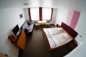 ein Schlafzimmer mit einem Bett und ein Wohnzimmer mit einer Couch in der Unterkunft Hotel Werdumer Hof in Werdum + 1 Foto