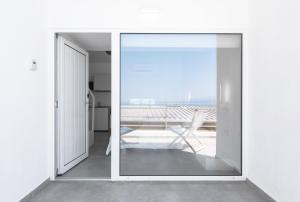 a sliding glass door leading to a patio with a chair at Twiins Studios by halu! - Next to Kallithea Beach in Kallithea Halkidikis