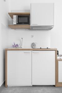 a kitchen with white cabinets and a microwave at Twiins Studios by halu! - Next to Kallithea Beach in Kallithea Halkidikis