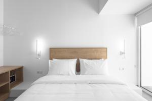 a white bedroom with a large bed with white pillows at Twiins Studios by halu! - Next to Kallithea Beach in Kallithea Halkidikis