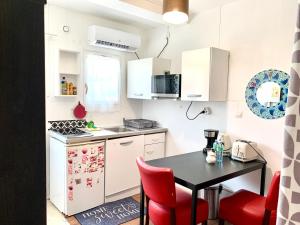 a small kitchen with a black table and red chairs at MaisonTevy - Appart 2 Chambres-4lits-Terrasse-Jardin & Studio-Confort-Climatisation- Idéale-Pro-Tourisme in Pontault-Combault