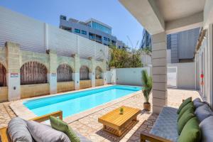 a swimming pool with a wooden table next to a building at Stunning villa w Private pool TT table Sleeps 14 in St. Julianʼs