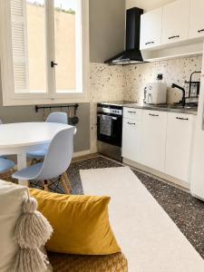 a kitchen with white cabinets and a table with a yellow pillow at Retro Apartment Patras in Patra