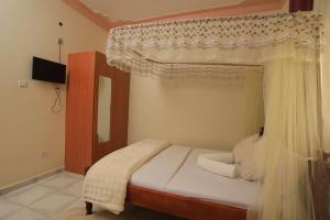 a bedroom with a canopy bed and a television at Grand View Hotel in Fort Portal