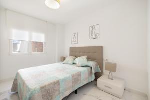a white bedroom with a bed and a lamp at Apartamento Calafell Mar in Calafell