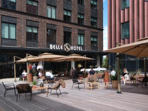 a patio with tables and chairs and umbrellas in front of a building at Belle Guldsmeden in Aarhus