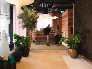 a person standing in a room with potted plants at Belle Guldsmeden in Aarhus