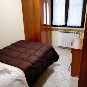 a bedroom with a bed and a desk and a window at Casa dei Nipotini con Posto Auto Riservato in Paganica