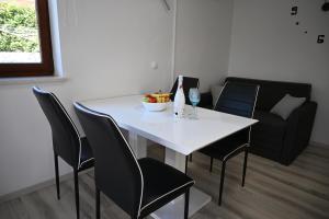 a white table with chairs and a bowl of fruit on it at Apartma Mija - XL in Kornić