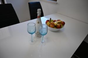 a bottle of champagne and two glasses on a table with a bowl of fruit at Apartma Mija - XL in Kornić
