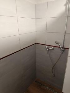 a shower with a hose in a tiled bathroom at Chalúpka Liptov in Lúčky +1 photo