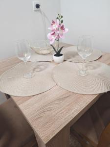 a wooden table with two wine glasses and a flower at Apartmani Peric Bogatic in Bogatić