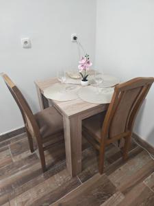 a wooden table with two chairs and a table with wine glasses at Apartmani Peric Bogatic in Bogatić
