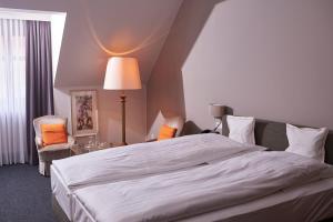ein Schlafzimmer mit einem großen weißen Bett und einer Lampe in der Unterkunft Hotel Goldener Karpfen OHG in Fulda
